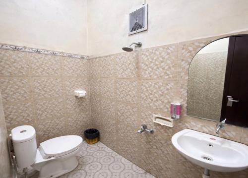 a bathroom with a toilet and a sink and a mirror at Parama Bromo Hotel in Ngadisari