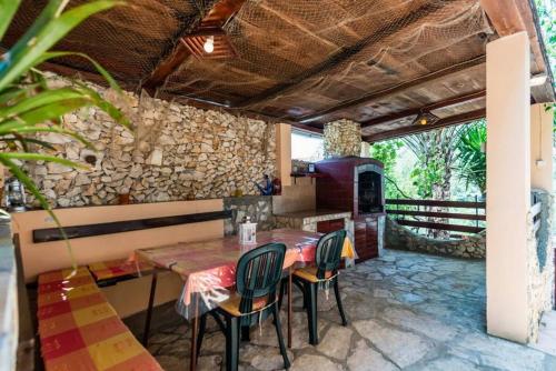 a kitchen with a table and chairs and a stone wall at Apartment Vesna in Vela Luka