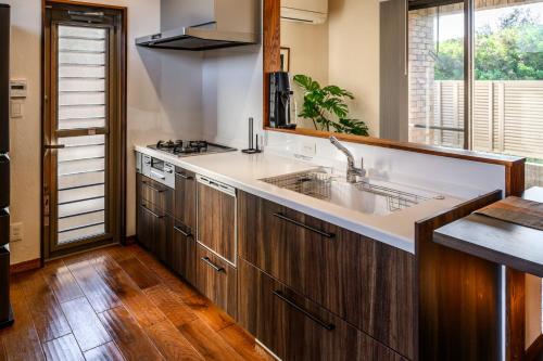 a kitchen with wooden cabinets and a sink at The Villa Miyako in Hirara
