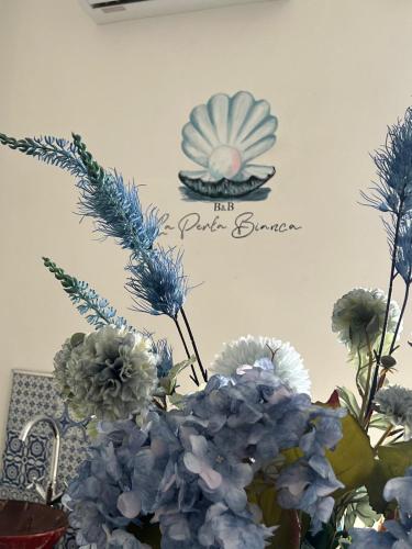 a vase with blue flowers and a sign on a wall at B&B 3 Stelle - La perla bianca in Càbras