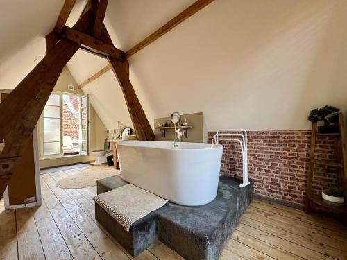 a bathroom with a white tub and a brick wall at La cour des grands in Arras