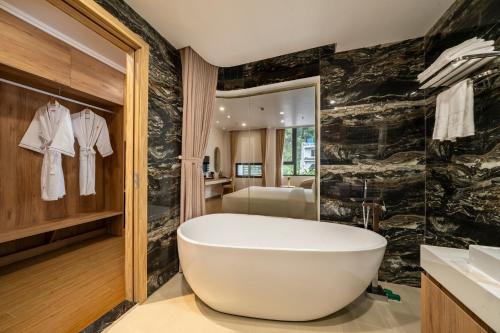 a bathroom with a large tub and a bedroom at Catba Vista Hotel - New 2026 - Infinity Pool in Cat Ba