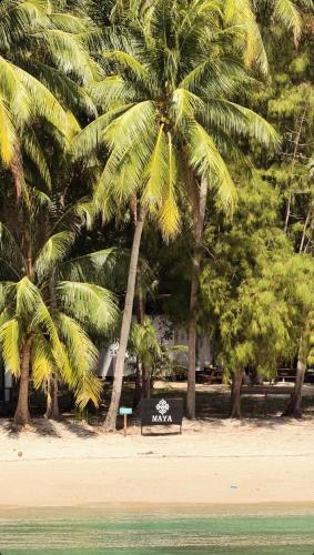 a bench sitting under two palm trees on a beach at Maya Seaview Chalet, Coral Bay Perhentian Island in Perhentian Island