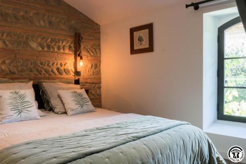 a bedroom with a bed with a stone wall at Le sourire des anges 2 in Saint-Élix-le-Château