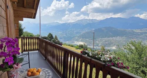 a balcony with a table and flowers and mountains at Chalet panoramique avec vue alpine à 180 degrés - poêle scandinave & nature in Grône