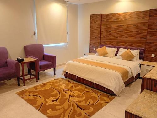 a bedroom with a large bed with two chairs and a table at شقق ليالي الشاطئ in Al Qunfudhah