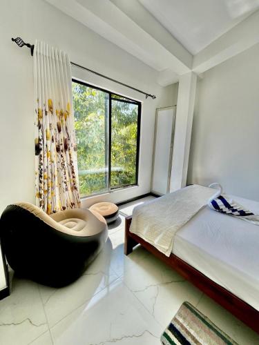 a bedroom with a bed and a chair and a window at Lavenia Mountain Holiday home in Bandarawela