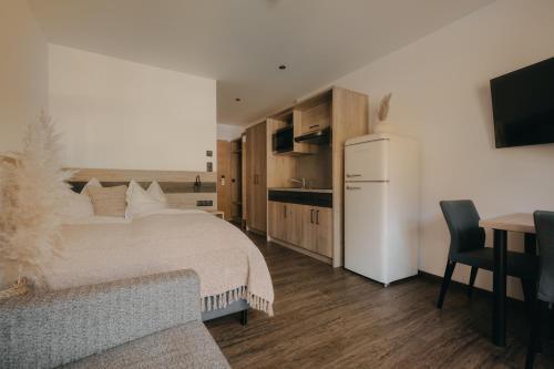 a bedroom with a white bed and a kitchen at Rössl Lodge in Gerlos