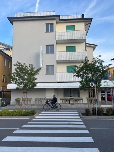 Ein Mann fährt mit dem Fahrrad vor einem Gebäude in der Unterkunft Hotel Al Capitano in Caorle