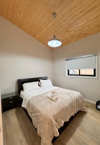 a bedroom with a large bed with a wooden ceiling at Winterwood Lodge - 6mins Jindabyne -Pets Allow-Floor Heating Winter-Swimming Pool Summer in Moonbah