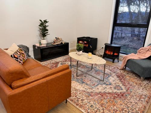 a living room with a couch and a table at Winterwood Lodge - 6mins Jindabyne -Pets Allow-Floor Heating Winter-Swimming Pool Summer in Moonbah