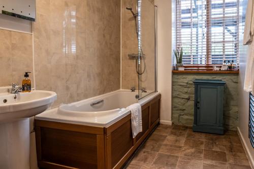 a bathroom with a tub and a sink and a bath tub at Ty Mawr, Brechfa in Carmarthen
