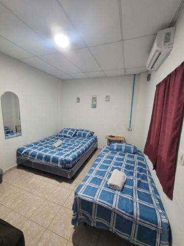 two beds sitting in a room with at Hostal viroleño in Zacatecoluca