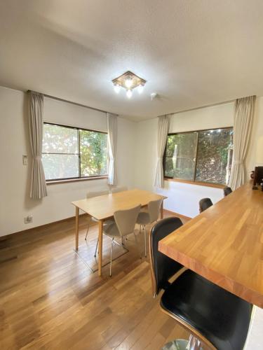 a dining room with a table and chairs and windows at トラストメゾン西伊豆 in Ukusu