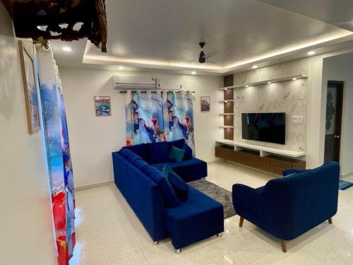 a living room with blue couches and a flat screen tv at Tropical Haven in Panaji