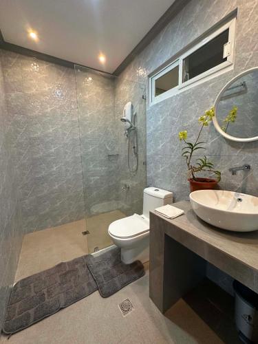a bathroom with a shower and a toilet and a sink at Green Field Resort Hotel in Anda