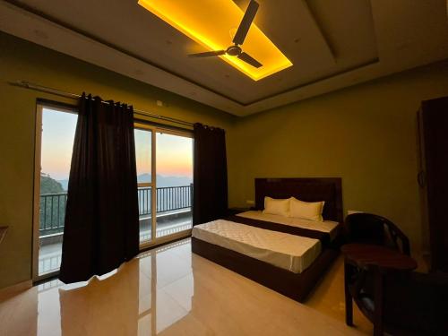 a bedroom with a bed with a ceiling fan and a balcony at Naman Eco Resort in Solan