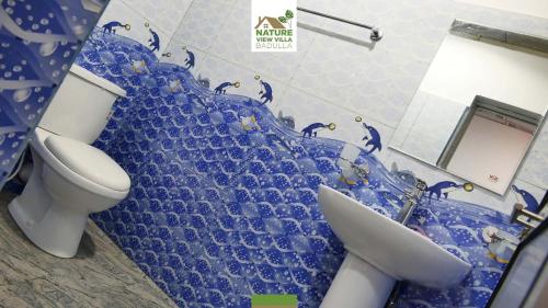 a bathroom with a toilet and a blue wall at Nature View Villa in Badulla