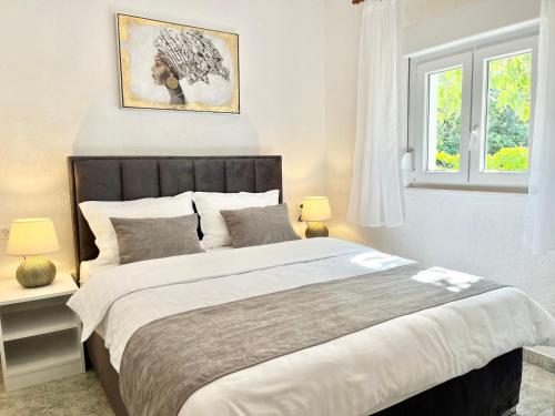 a bedroom with a large bed and two windows at Apartments Fortuna in Biograd na Moru