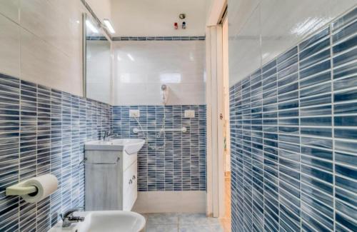 a bathroom with a sink and a shower with blue tiles at Villa Florence apartment con parcheggio in Torre Lapillo