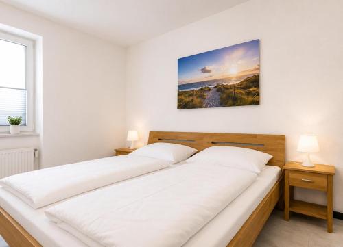 two beds in a white room with two lamps at Terrassenhaus Whg 21 in Duhnen