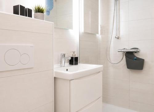 a white bathroom with a sink and a shower at Terrassenhaus Whg 21 in Duhnen