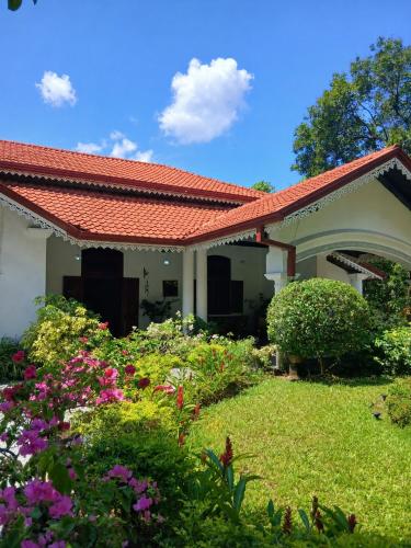 a house with a red roof and some flowers at Kithulvilla Holiday Bungalow in Kitulgala