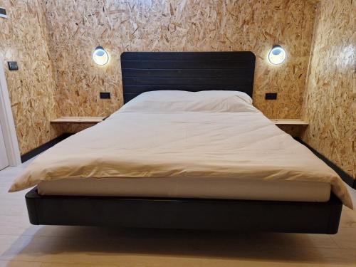 a bed in a bedroom with two lights on the wall at Căsuța Piticilor in Broşteni