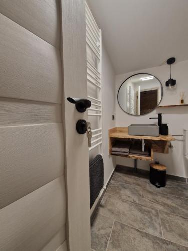 a door in a bathroom with a vanity and a mirror at Căsuța Piticilor in Broşteni