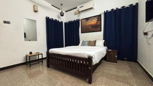 a bedroom with a bed with blue curtains at Coliveinn in Ernakulam