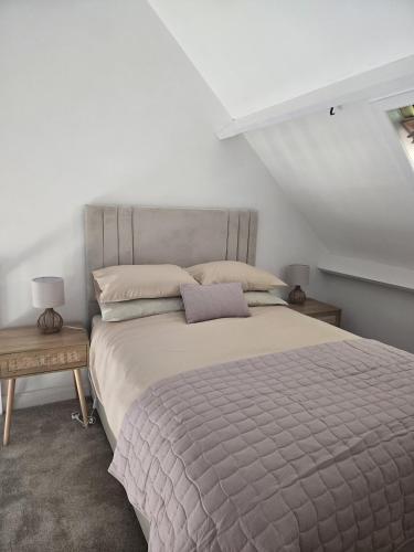 a bedroom with a large bed and two tables at Cosy Moat House Cottage #2 in Pembroke