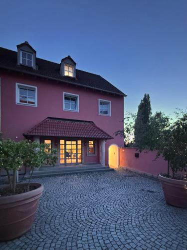 a large pink house with a brick driveway at feinzeit am Windfelder See - Ruhe & Natur nahe Bamberg in Stegaurach