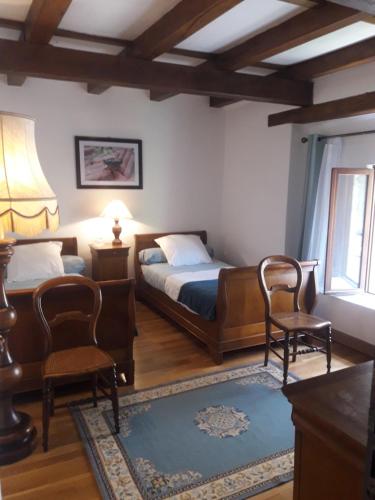 a bedroom with two beds and two chairs and a window at Gîte Le Pont du Soleil in Hyds