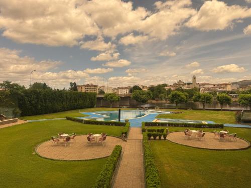 a garden with tables and chairs and a swimming pool at Grande Hotel Dom Dinis in Mirandela