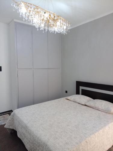 a white bedroom with a bed and a chandelier at Hera's apartment in Porto Rafti