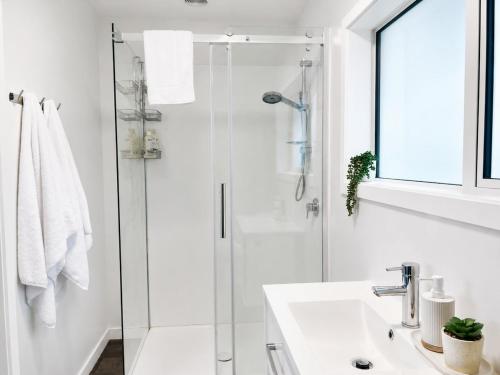a white bathroom with a shower and a sink at The Burnby in Te Anau