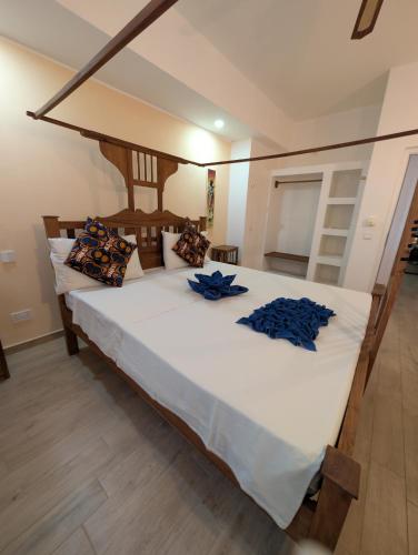 a bedroom with a large white bed with blue pillows at Thamani Apartment Zanzibar in Pwani Mchangani