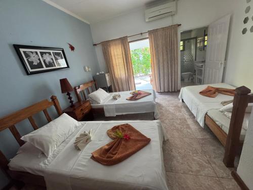 a hotel room with two beds and a table at Villa Rafia in Baie Sainte Anne