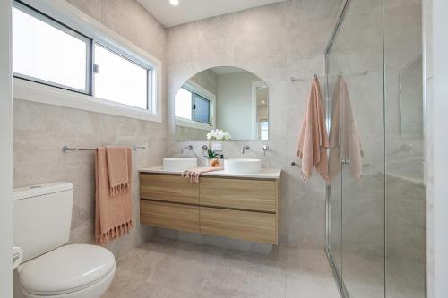 a bathroom with a shower and a toilet and a sink at Basalt Beach House in Bargara
