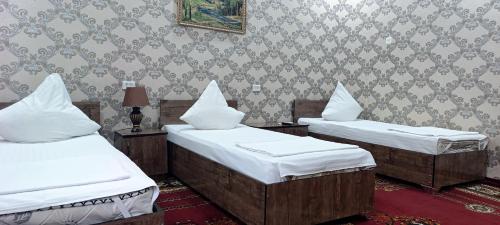 two twin beds in a room with wallpaper at Mubina Khiva B&B in Khiva