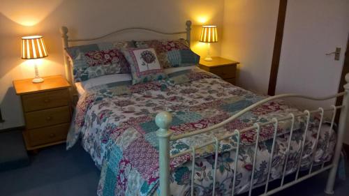 a bedroom with a bed with a quilt and two lamps at Barnkirk Holidays in Newton Stewart