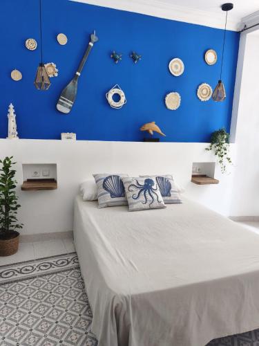 a bedroom with a blue wall and a bed with pillows at Habitaciones Andaluzas in Ronda