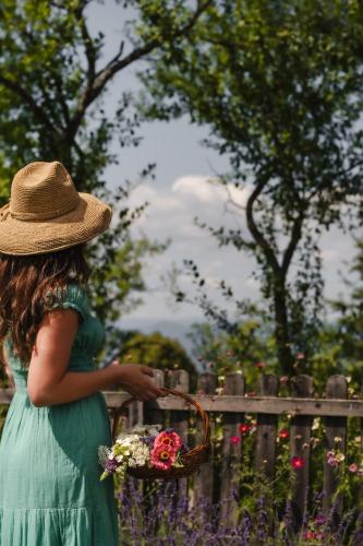 a woman in a hat holding a basket of flowers at Fairytale cottage Francka in Gorica pri Slivnici