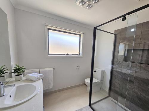 a bathroom with a shower and a sink and a toilet at St Germain House, Clyde North in Clyde North