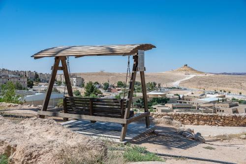 a swing on top of a hill with a city at הדירה של אייזיק - דירה מהממת במצפה רמון עם נוף מדהים in Mitzpe Ramon