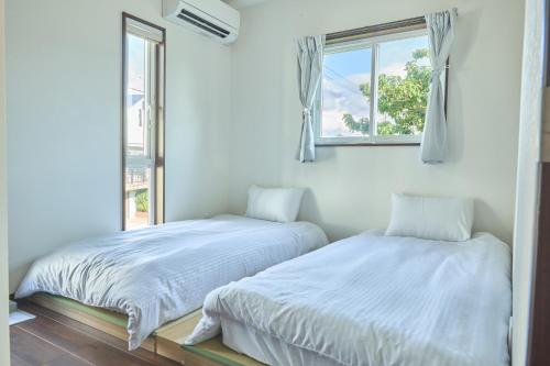 two beds in a room with a window at 甘口派Stay in Tsurumakida