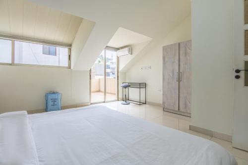 a white bedroom with a large bed and a window at Rooftop one BDR with Terrace in Al Bawsharīyah