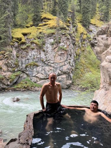 two men standing in a pool of water in a river at Asiya in Karakol