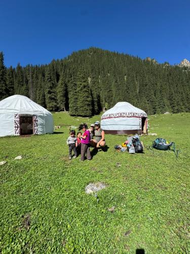 a group of people sitting in a field next to tents at Asiya in Karakol