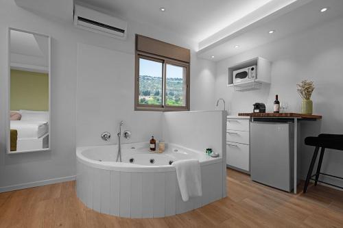 a white bathroom with a tub and a kitchen at Mikiway סוויטה פנורמית בגלבוע in Bet HaShitta